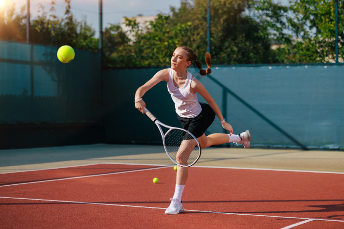 Female tennis player hitting a forehand shot during an outdoor tennis practice session on a hard court